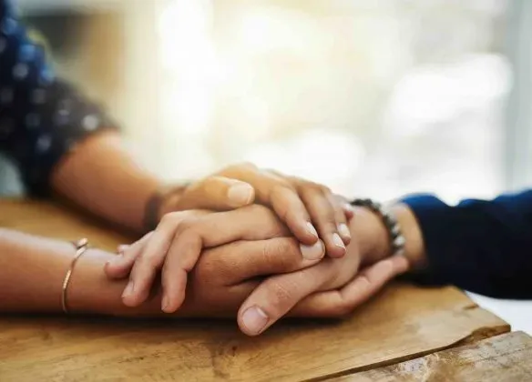 Geste de soutien et de réconfort entre deux personnes endeuillées.