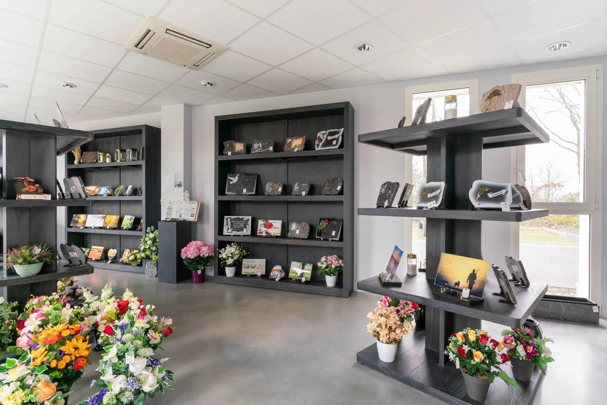 Intérieur du magasin Pompes Funèbres Martinez avec plaques et fleurs.